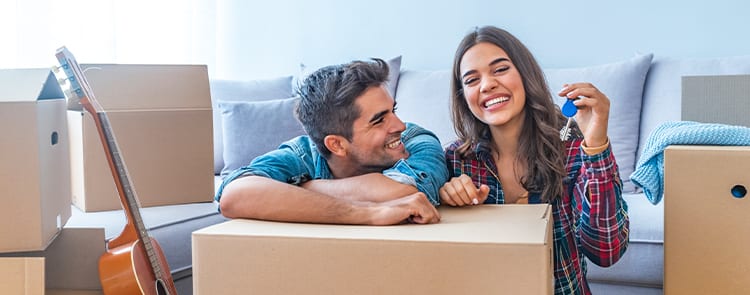 man and woman new homeowners unpacking boxes with keys in hand