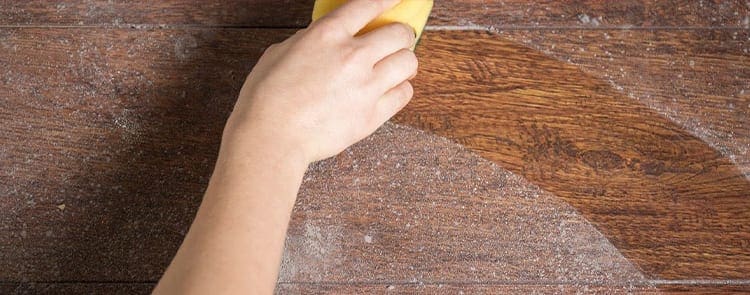 person dusting furniture in their house