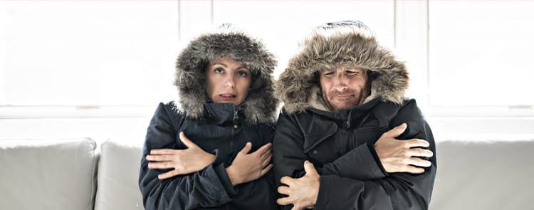 couple wearing their winter coats freezing in their home