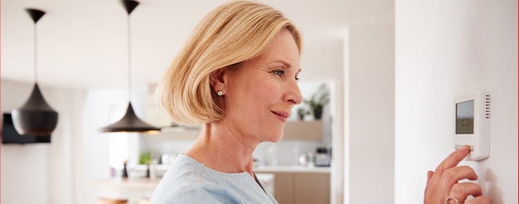 older woman checking thermostat