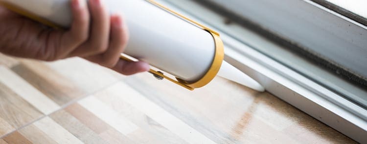 person caulking their window sill