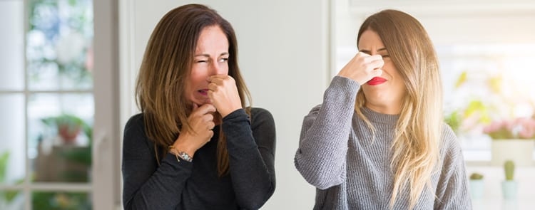 two women holding their noses because of a bad smell