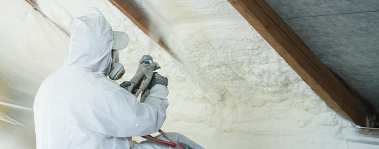 man in suit spray foaming attic